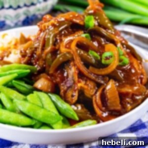 A serving of Slow Cooker Sweet and Tangy Pork Chops on a plate with sugar snap peas, ready to be enjoyed.