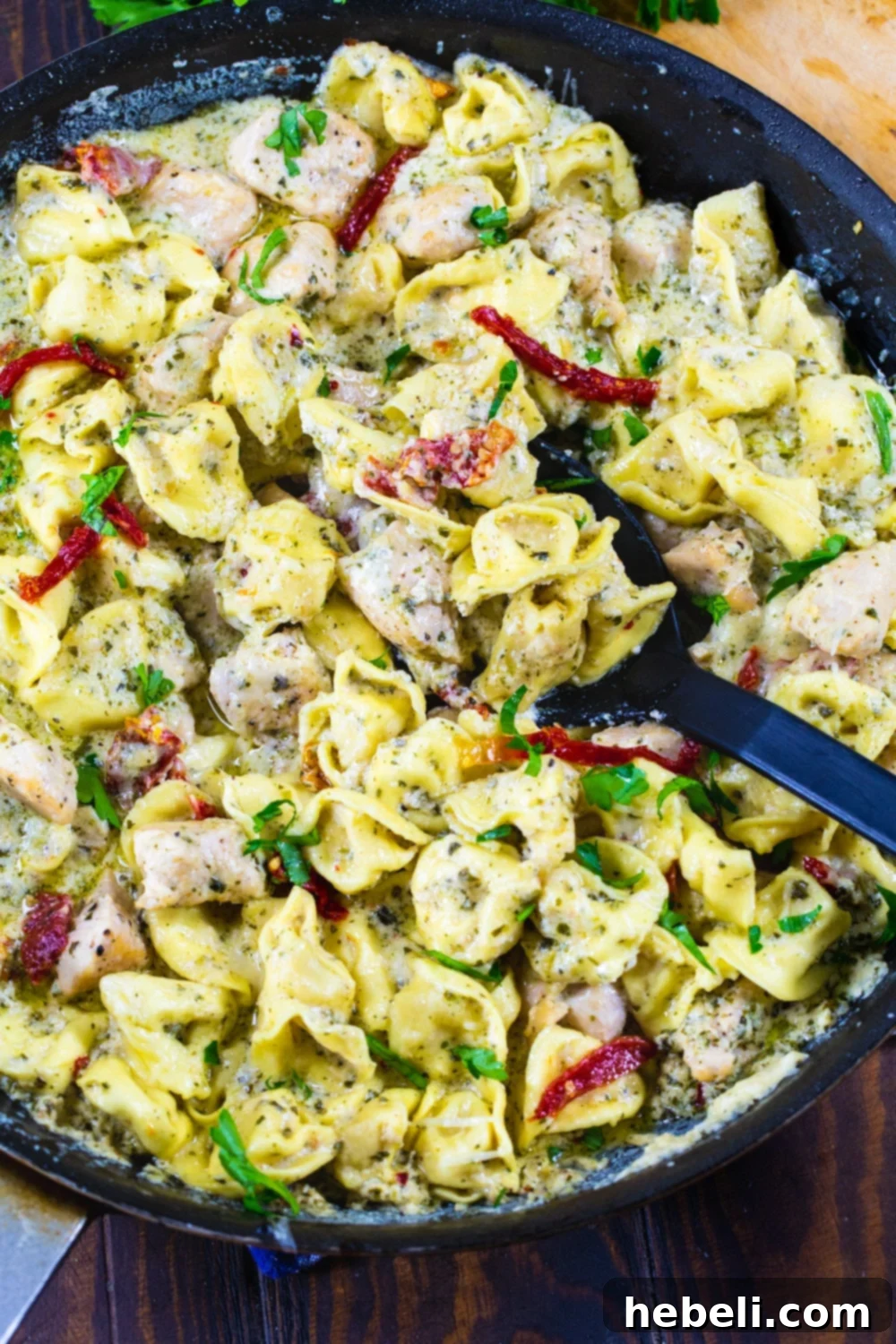 Creamy Chicken Pesto Tortellini 3 Close-up of Pesto Tortellini with Chicken and vibrant sun-dried tomatoes in a nonstick pan.