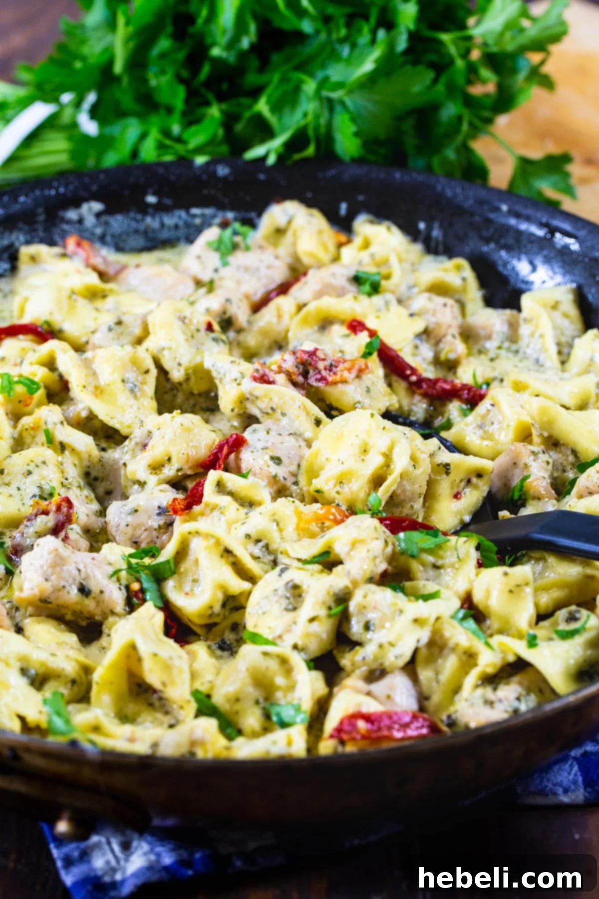 Creamy Chicken Pesto Tortellini 4 Pesto Tortellini in a skillet with fresh parsley garnish, ready for serving.