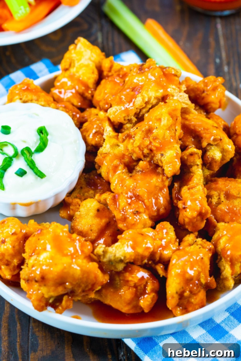 Zesty Buffalo Chicken Bites 3 Close-up of crispy chicken nuggets generously coated in a vibrant Buffalo sauce, served on a plate.