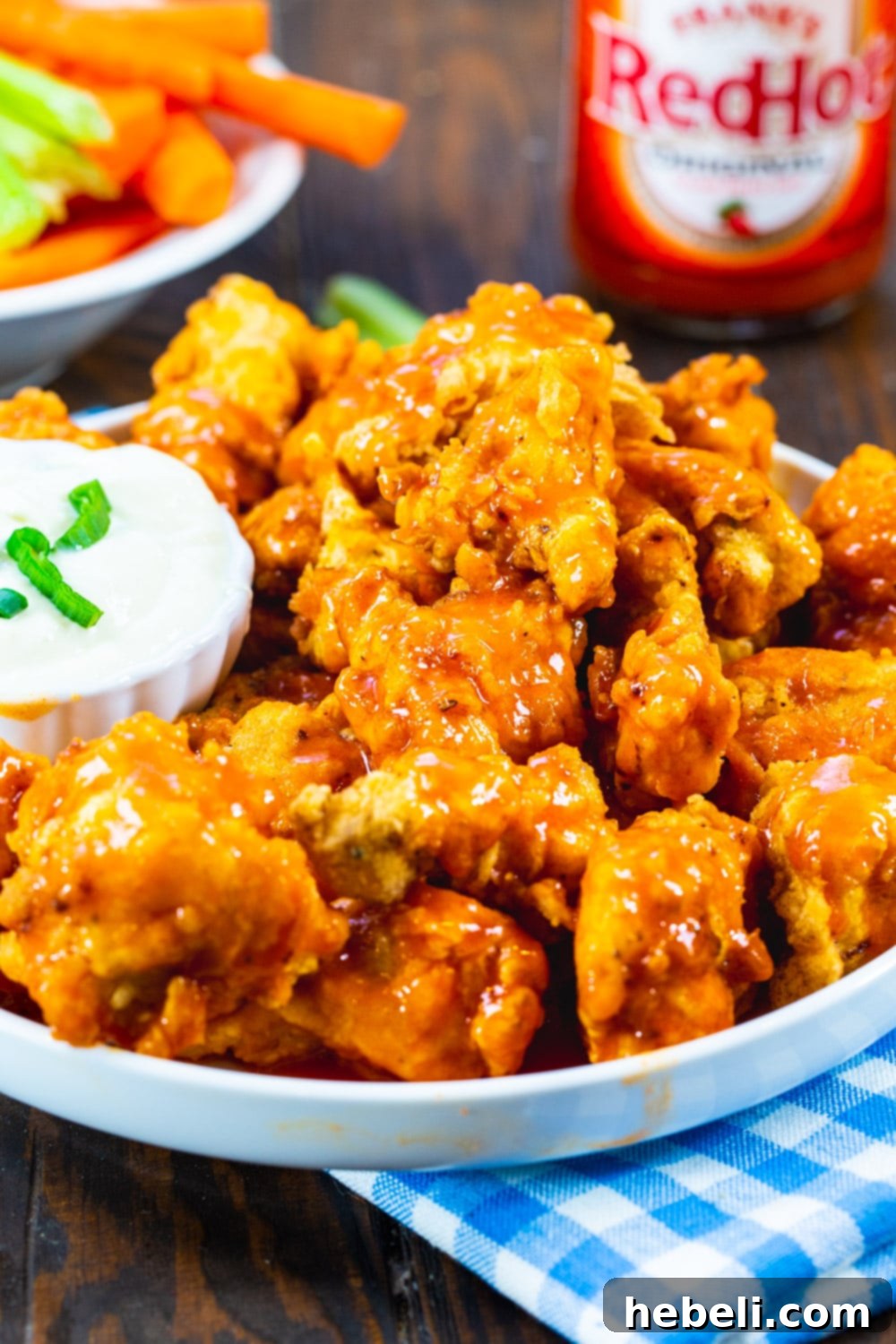 Zesty Buffalo Chicken Bites 4 A plate of delicious Buffalo Chicken Nuggets, with a bottle of hot sauce subtly blurred in the background, hinting at their spicy flavor.