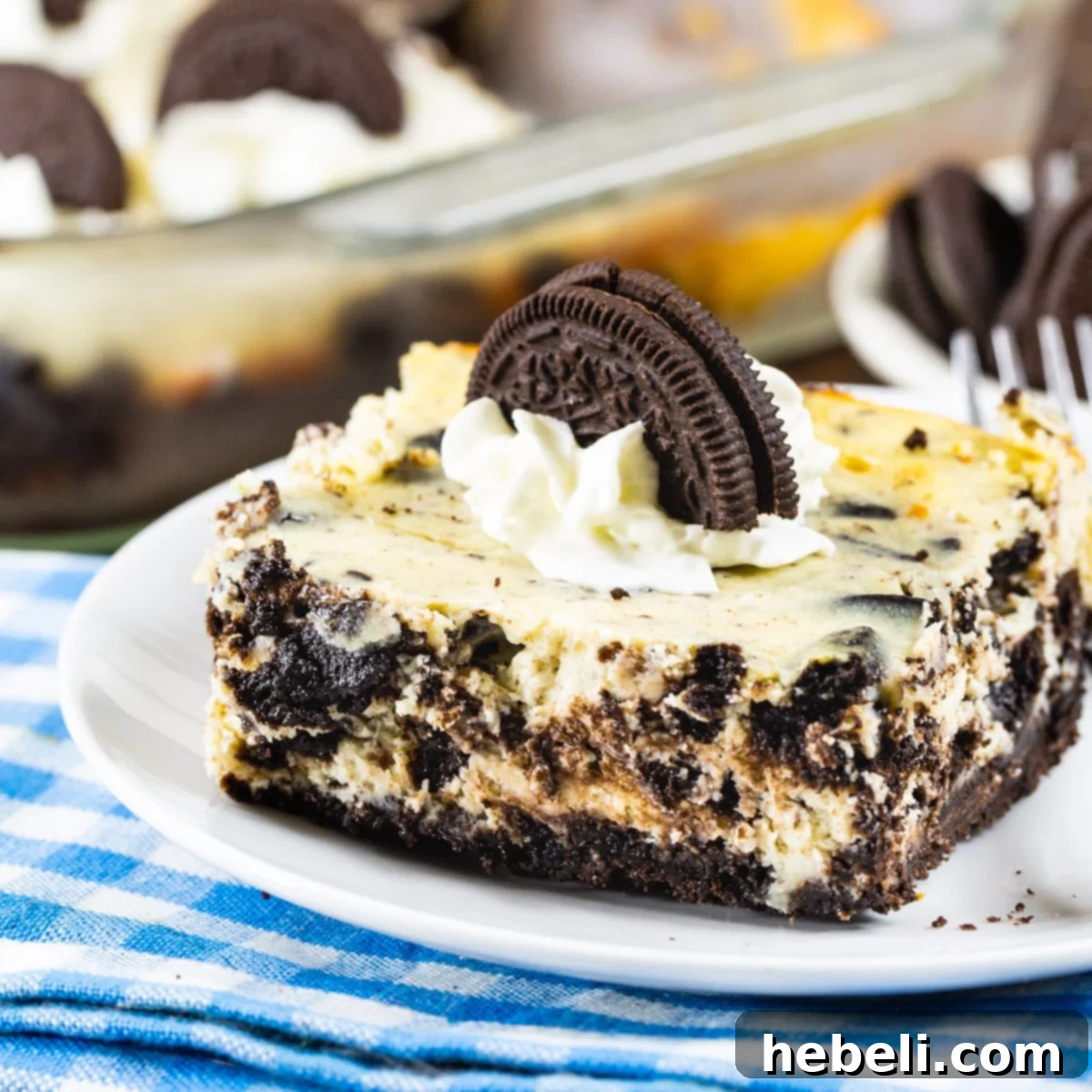 Decadent Oreo Cheesecake Bars topped with fluffy whipped cream and a sprinkle of Oreo crumbs.