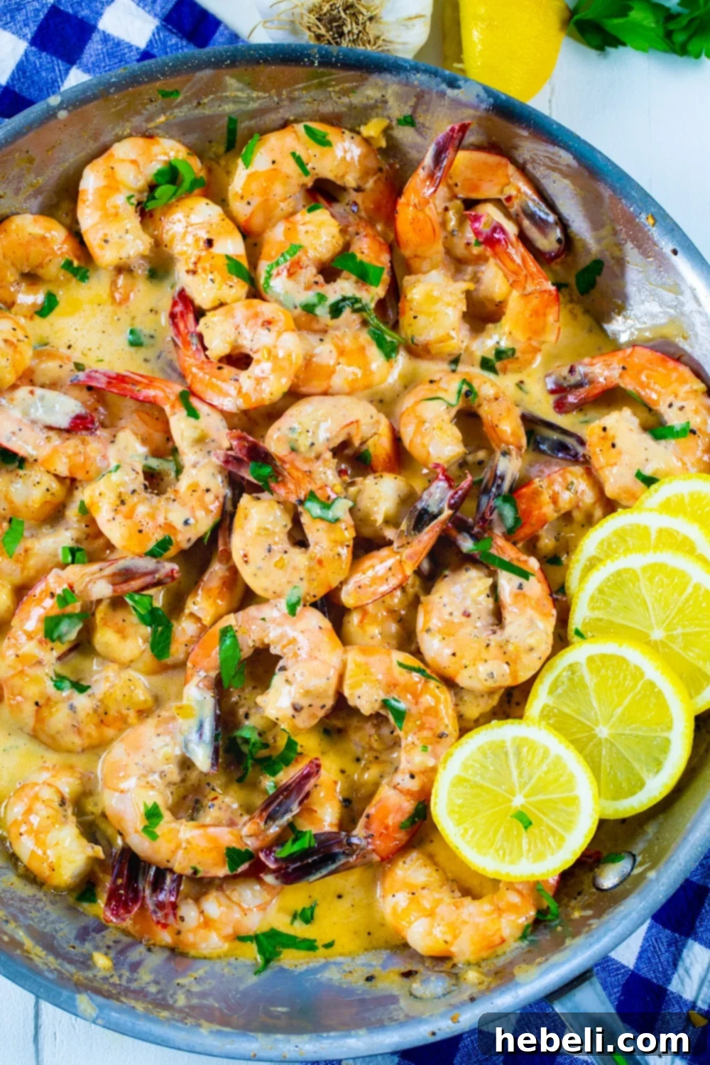 Cooked creamy lemon garlic butter shrimp in a skillet with lemon slices and parsley garnish.