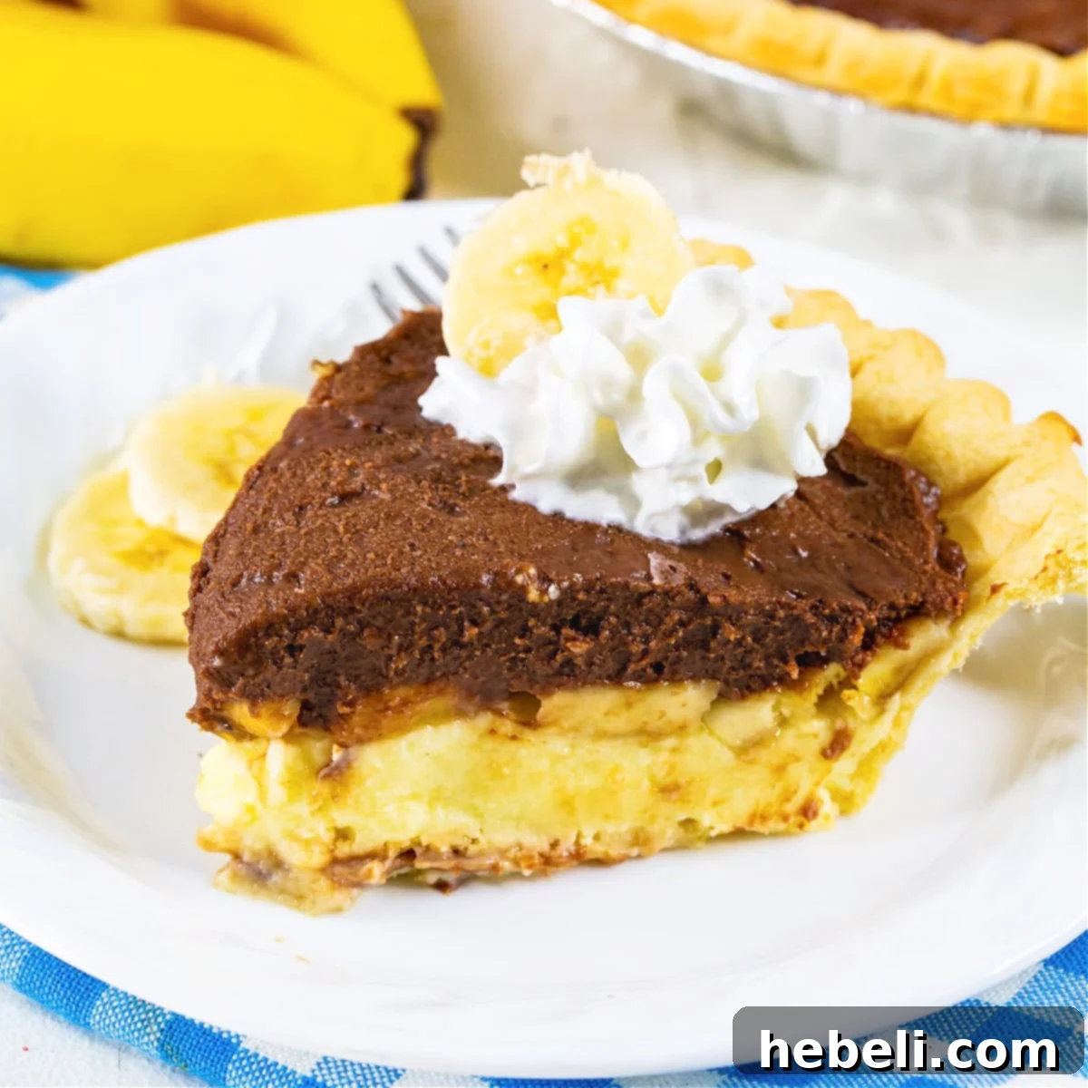 Creamy Chocolate Banana Bliss 2 A beautifully sliced piece of Chocolate Banana Cream Pie on a white plate, showcasing its distinct banana and chocolate layers and a dollop of whipped cream.