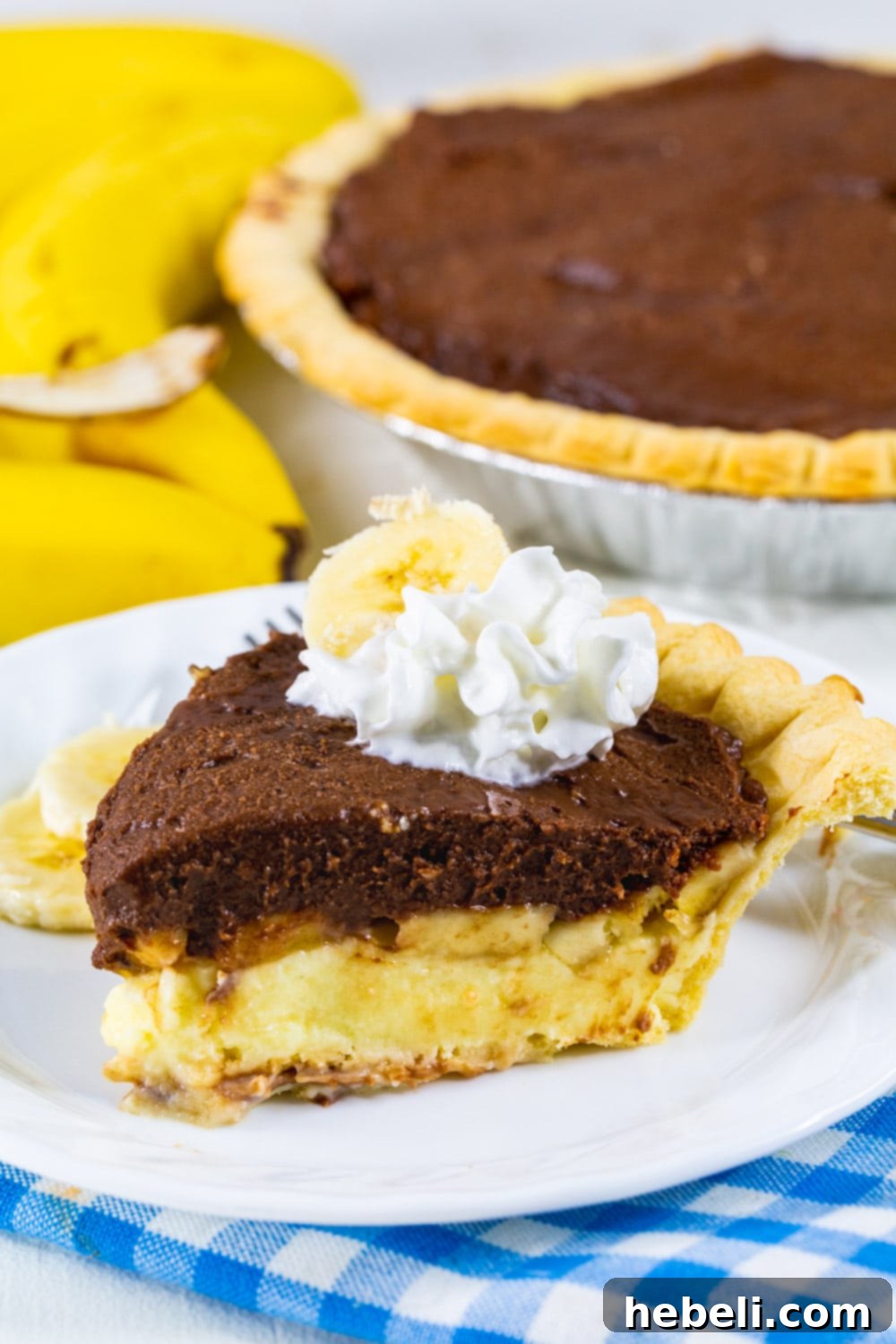 Creamy Chocolate Banana Bliss 5 A close-up of a slice of Chocolate Banana Cream Pie, highlighting the smooth chocolate layer, the perfectly arranged banana slices, and the creamy banana layer below, garnished with a generous dollop of whipped cream.