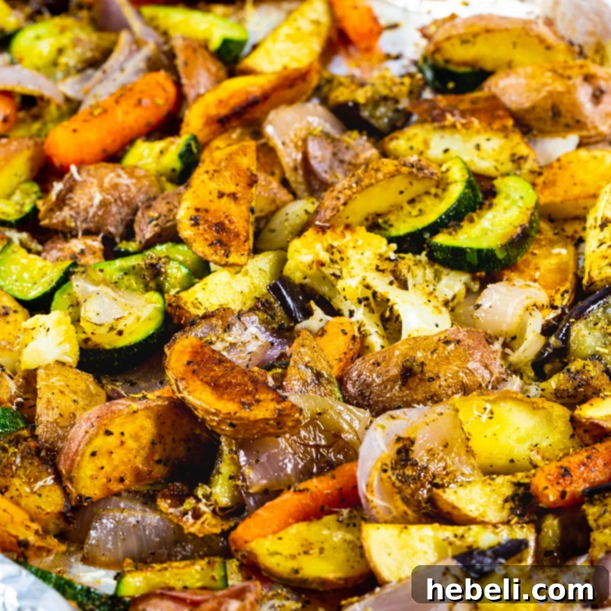 A large baking sheet filled with perfectly roasted Italian vegetables, including golden-brown potatoes, tender zucchini, caramelized red onion, and vibrant carrots, seasoned with Tuscan herbs and ready for serving.