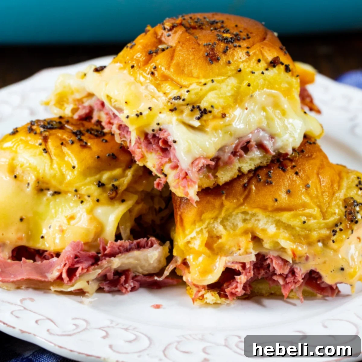 A plate piled high with golden-brown Baked Reuben Sliders, showcasing their melted Swiss cheese and flavorful corned beef.