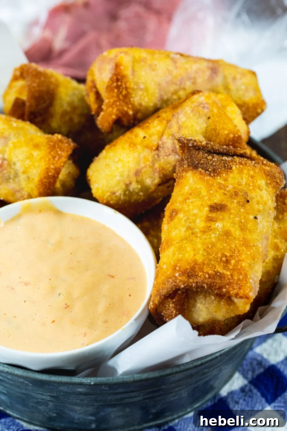 A batch of freshly fried Reuben Egg Rolls, golden and crisp, served in a rustic metal dish, perfect for sharing.
