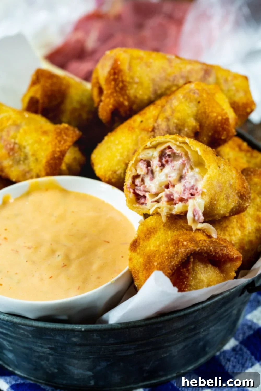 A Reuben Egg Roll cut in half, revealing the creamy, savory filling of corned beef, sauerkraut, and melted Swiss cheese.