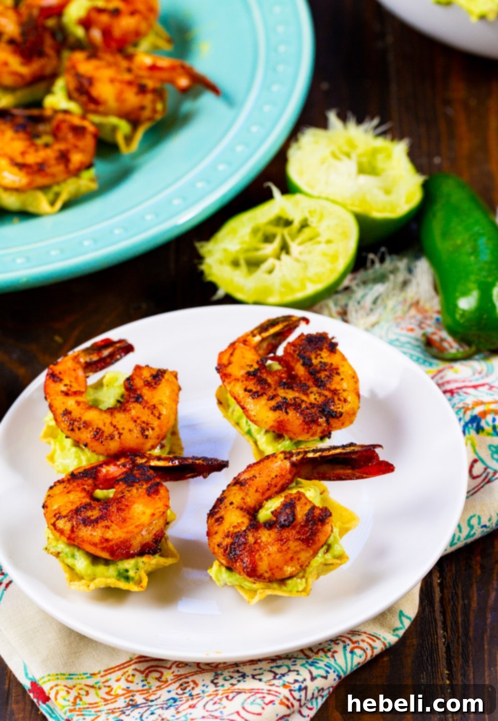 A serving platter with Shrimp Tostada Bites and fresh lime halves, emphasizing the vibrant colors and fresh ingredients.