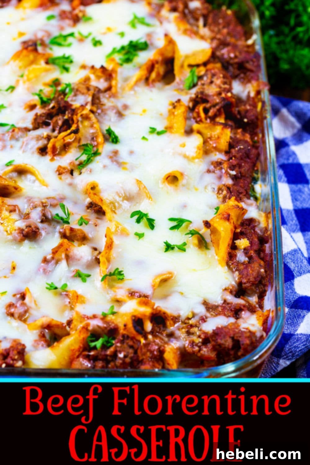 A top-down shot of the Beef Florentine Casserole in a baking dish, showcasing the vibrant green spinach, rich red sauce, and golden-brown melted cheese, with a corner piece ready to be served.