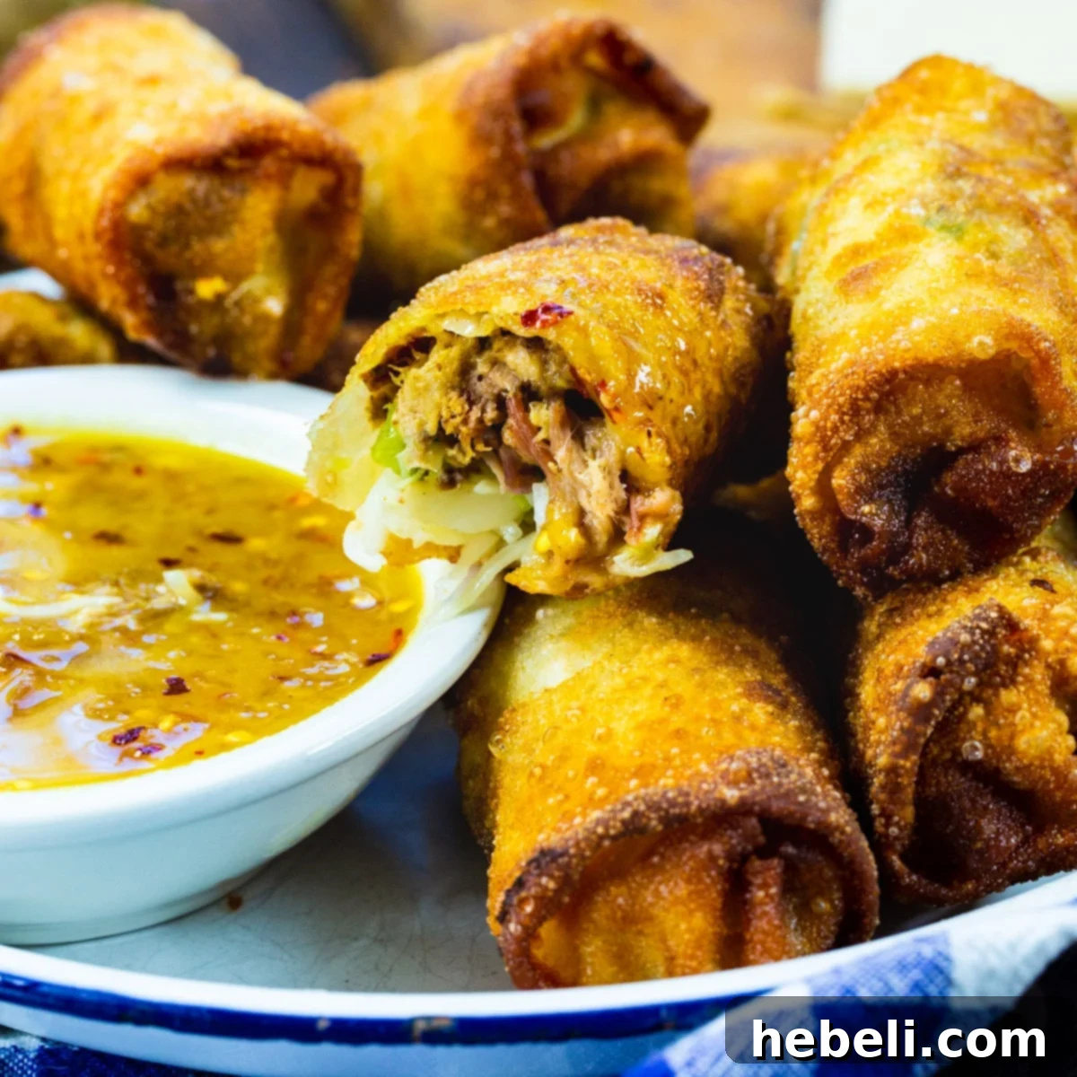 Smoky BBQ Pork Egg Rolls 2 Crispy Pulled Pork Egg Rolls served on a platter with a bowl of vibrant peach dipping sauce, perfect for gameday or parties.