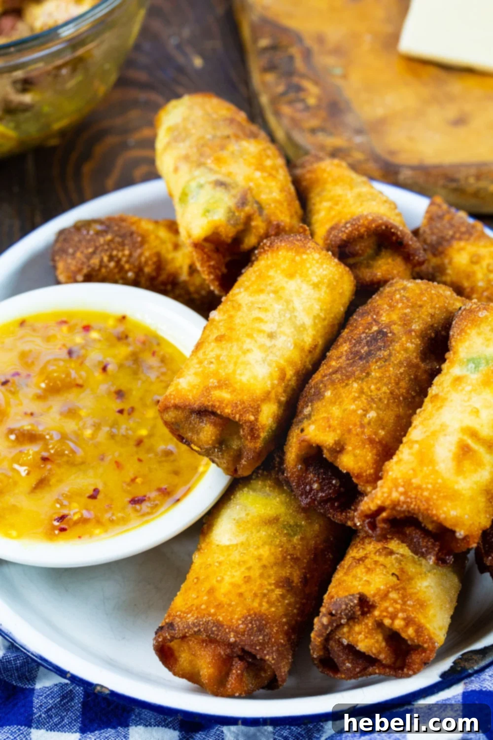 Smoky BBQ Pork Egg Rolls 3 A vibrant display of Pulled Pork Egg Rolls on a serving tray, accompanied by a small bowl of the bright peach dipping sauce, ready for guests.