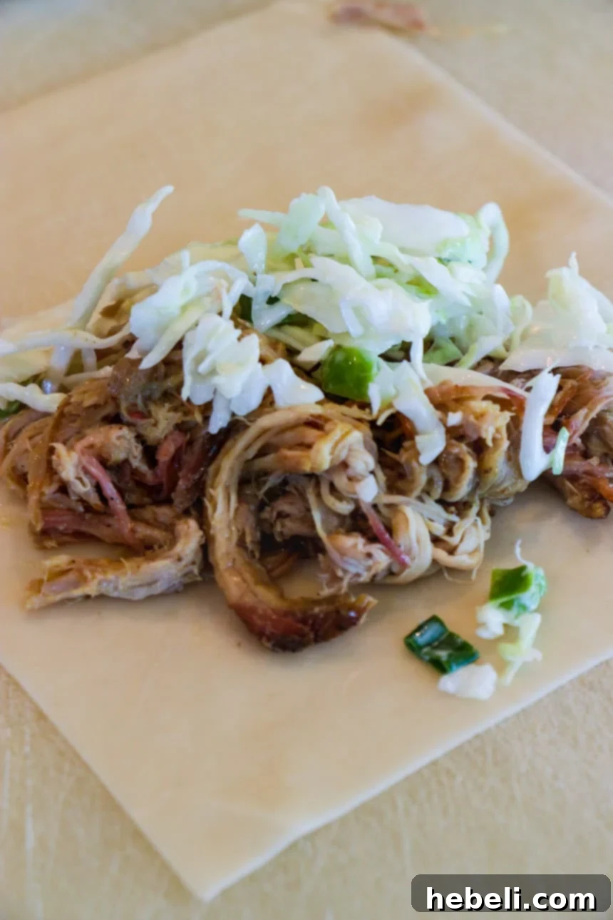 Smoky BBQ Pork Egg Rolls 4 Pulled pork and coleslaw arranged on an egg roll wrapper, ready for folding and frying.