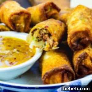 Pulled Pork Egg Rolls in serving tray with peach dipping sauce.