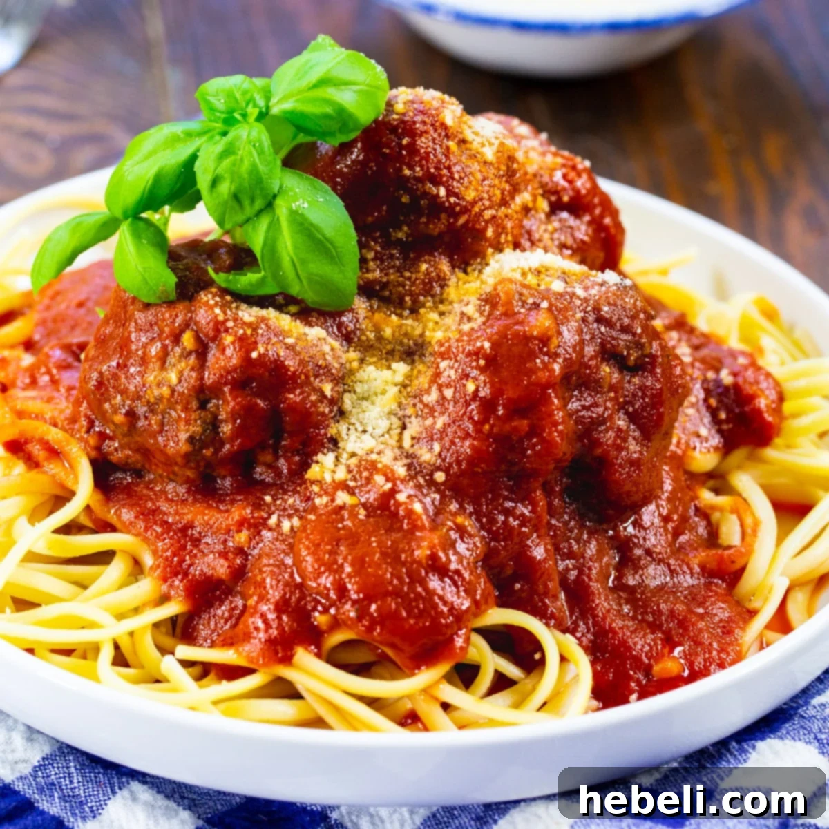 Delicious Slow Cooker Spicy Meatballs and Marinara served generously over a bed of spaghetti, garnished with fresh herbs.