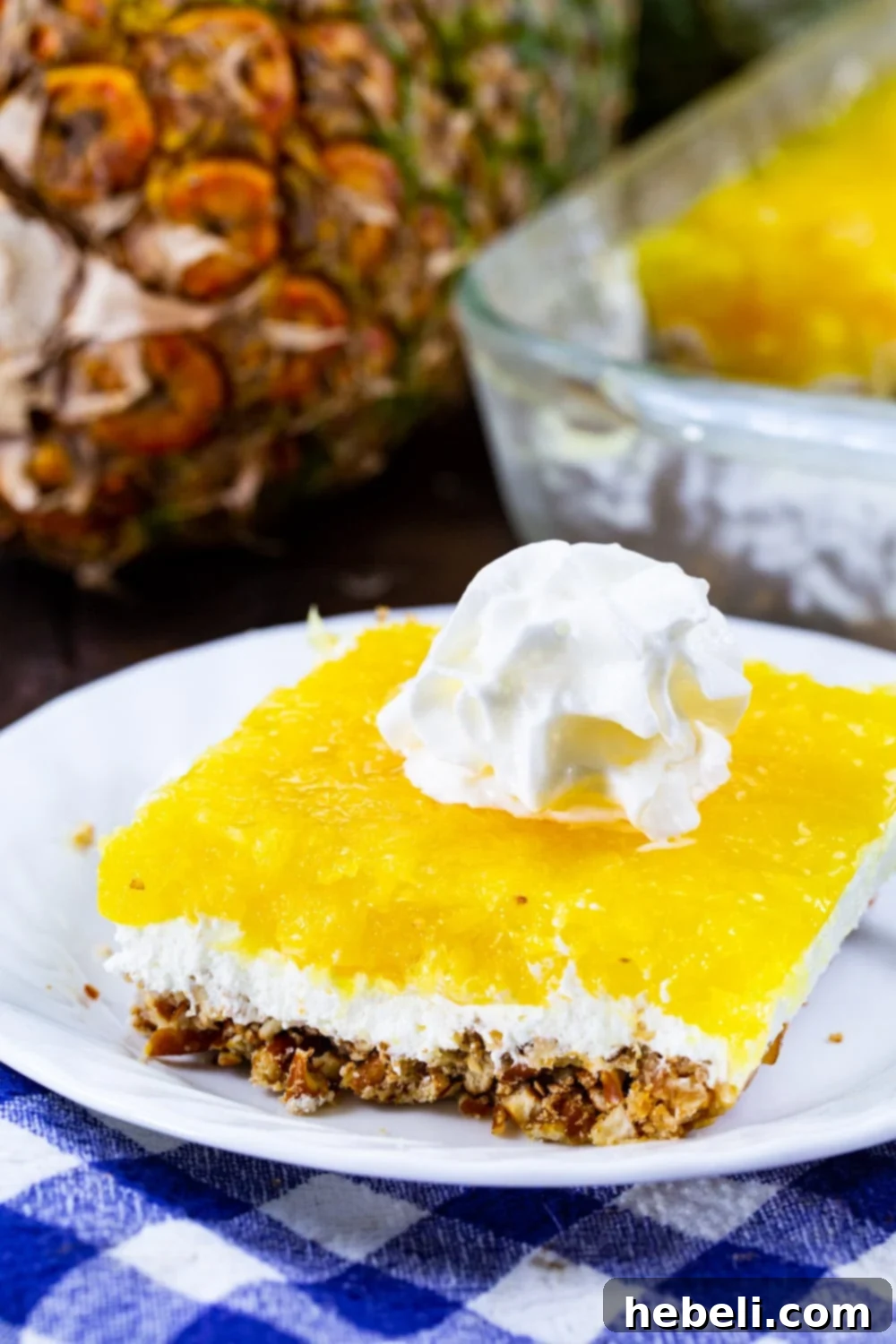 A slice of Pineapple Pretzel Salad on a plate, garnished with whipped cream, ready to be enjoyed.