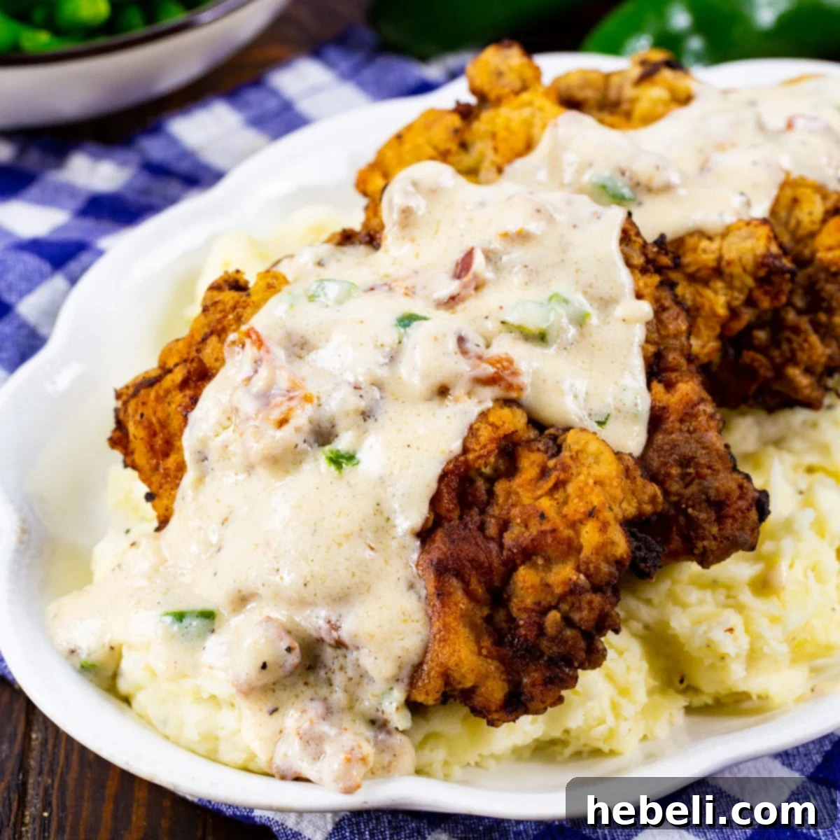Crispy Chicken Fried Steak generously topped with homemade Jalapeño Bacon Gravy, served alongside fluffy mashed potatoes.