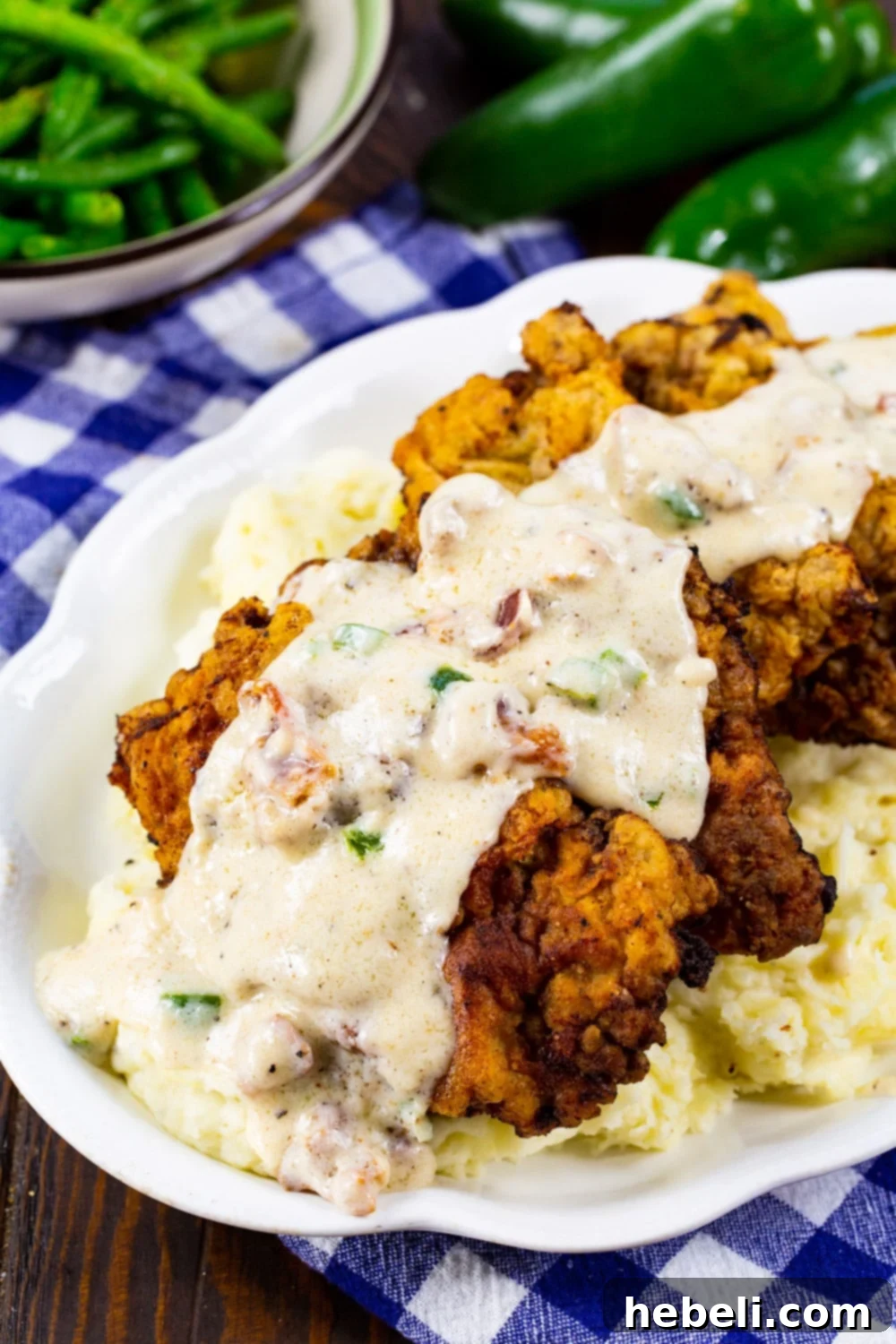 Close-up shot of Chicken Fried Steak covered in Jalapeño Bacon Gravy, served on a bed of creamy mashed potatoes.