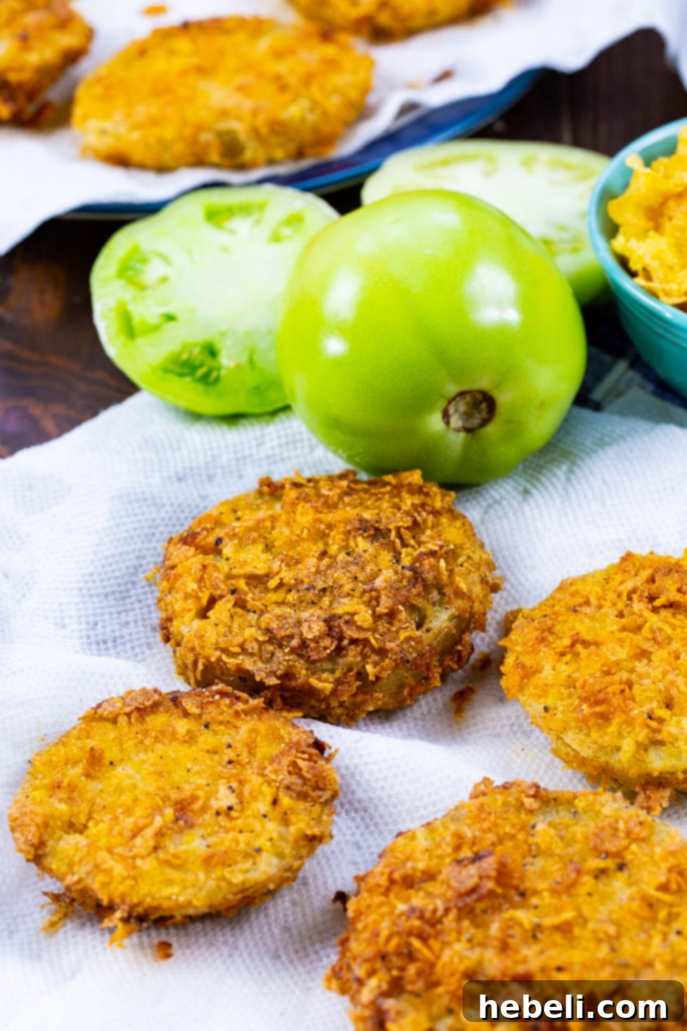 Fried green tomato slices on paper towels after draining excess oil.