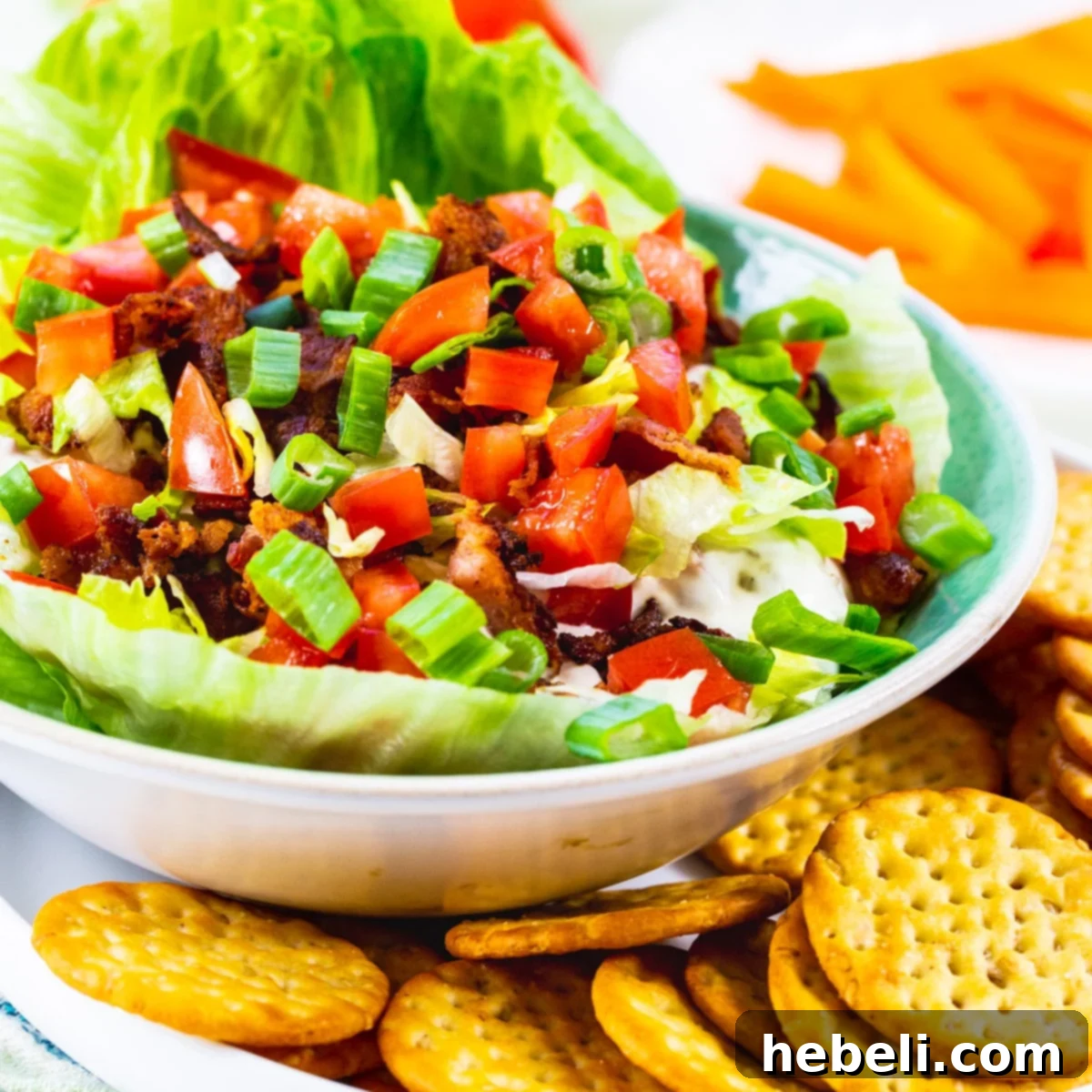 Creamy BLT Dip 2 BLT Dip in a rustic white bowl surrounded by crisp crackers, ready to be served at a party.