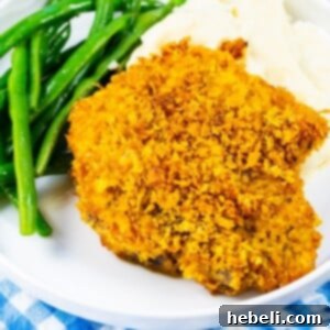 Cornflake Crusted Baked Pork Chops on plate with mashed potatoes and green beans.
