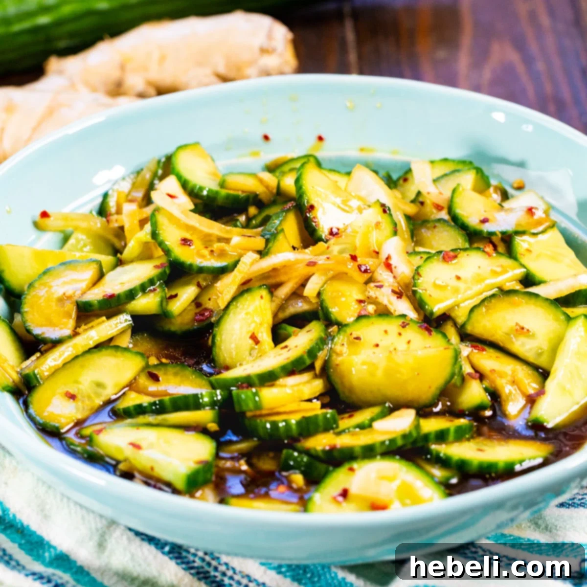 A beautifully arranged bowl of vibrant Ginger Sesame Cucumbers, showcasing thinly sliced cucumbers, fresh ginger matchsticks, and a glistening sesame dressing.