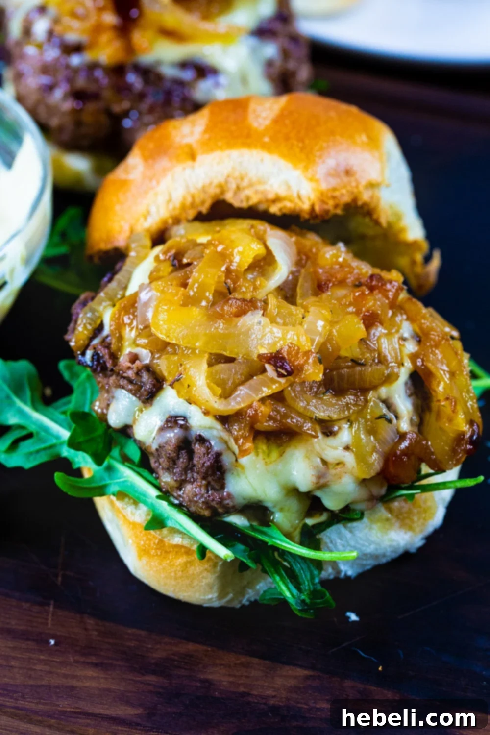 Caramelized onions gracefully layered on top of a burger patty with melted Gruyere cheese.