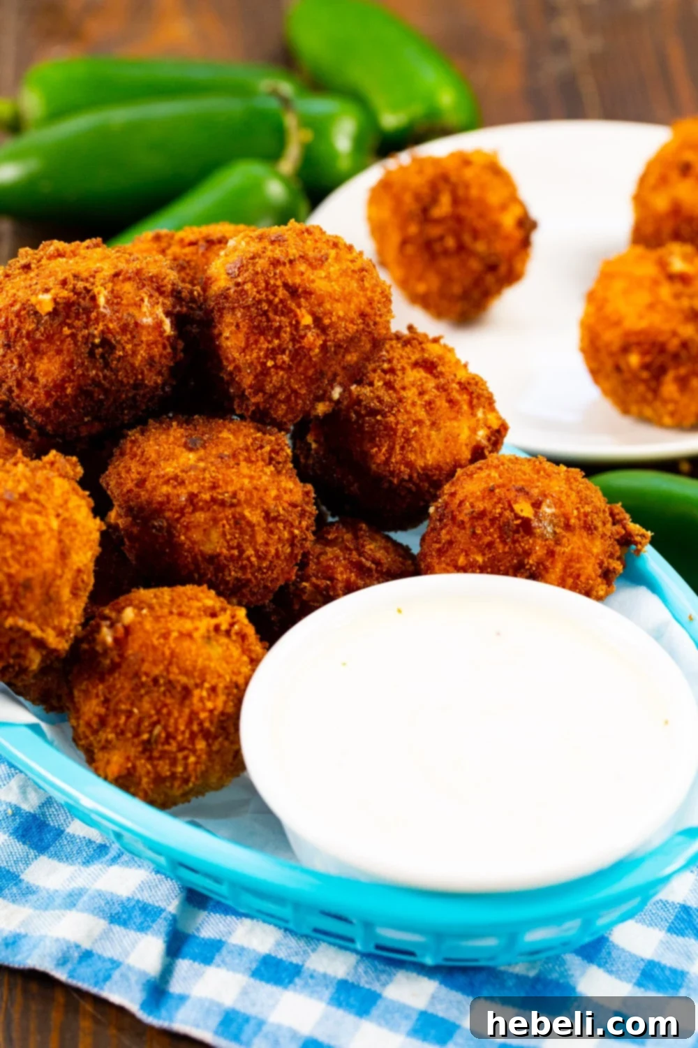 Crispy Jalapeno Poppers 3 Jalapeno Popper Bites arranged in a basket with a bowl of ranch dressing for dipping.