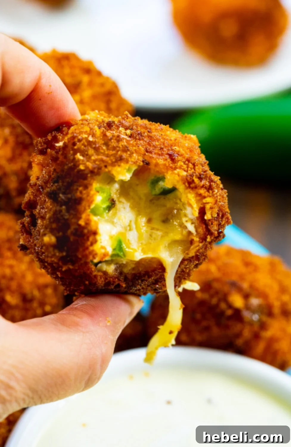 Crispy Jalapeno Poppers 4 A hand holding a perfectly golden-brown Fried Jalapeno Popper Bite.