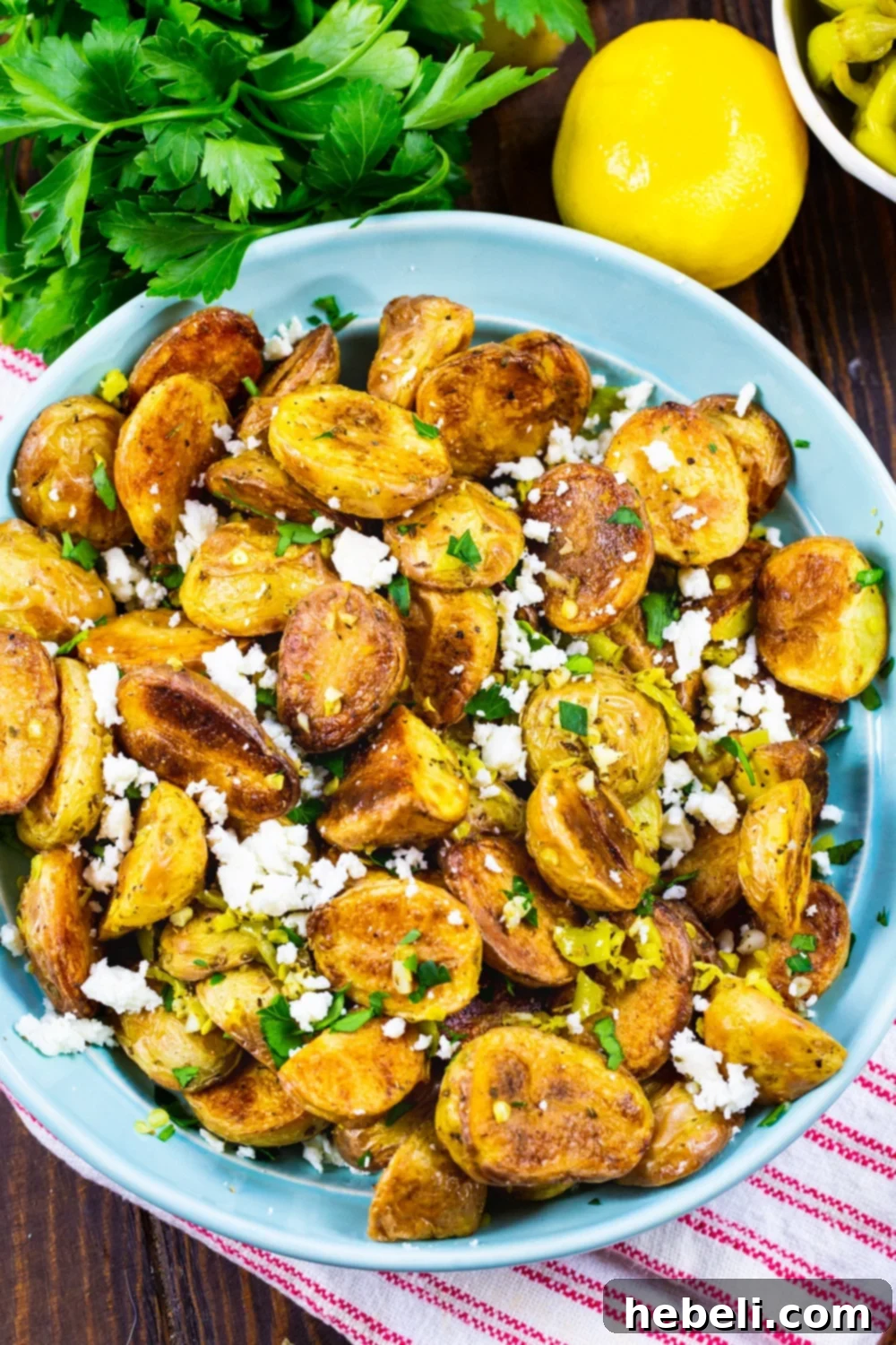 Classic Greek Lemon Potatoes 3 Roasted Greek Potatoes elegantly presented in a bowl, garnished with fresh parsley and lemon wedges, emphasizing their Mediterranean inspiration.