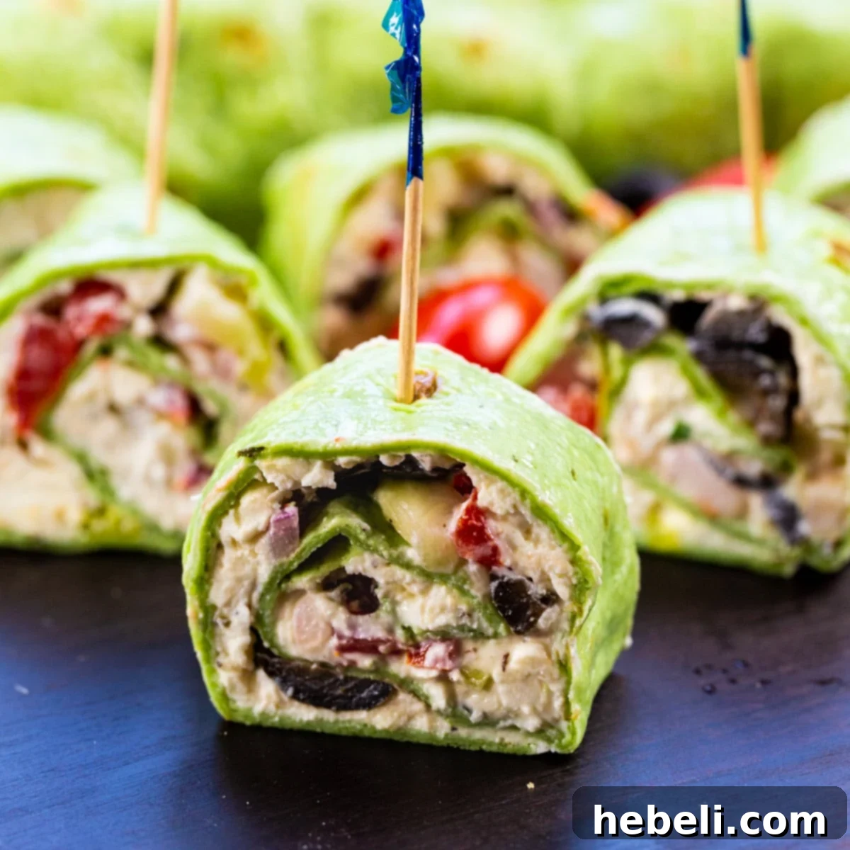 Mediterranean Swirl Appetizers 2 Greek Salad Pinwheels arranged beautifully on a rustic wooden cutting board, showcasing their vibrant colors and fresh ingredients.