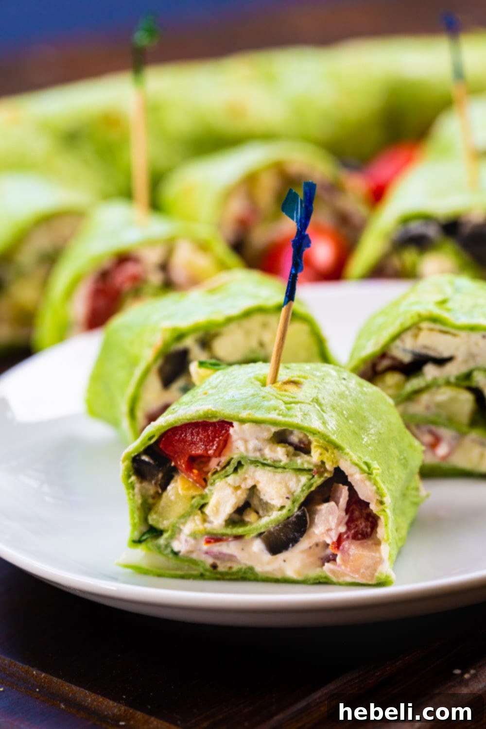 Mediterranean Swirl Appetizers 5 A plate of freshly cut Greek Salad Pinwheels, beautifully garnished and ready to serve, highlighting the vibrant colors of cucumbers, tomatoes, feta cheese, and olives.