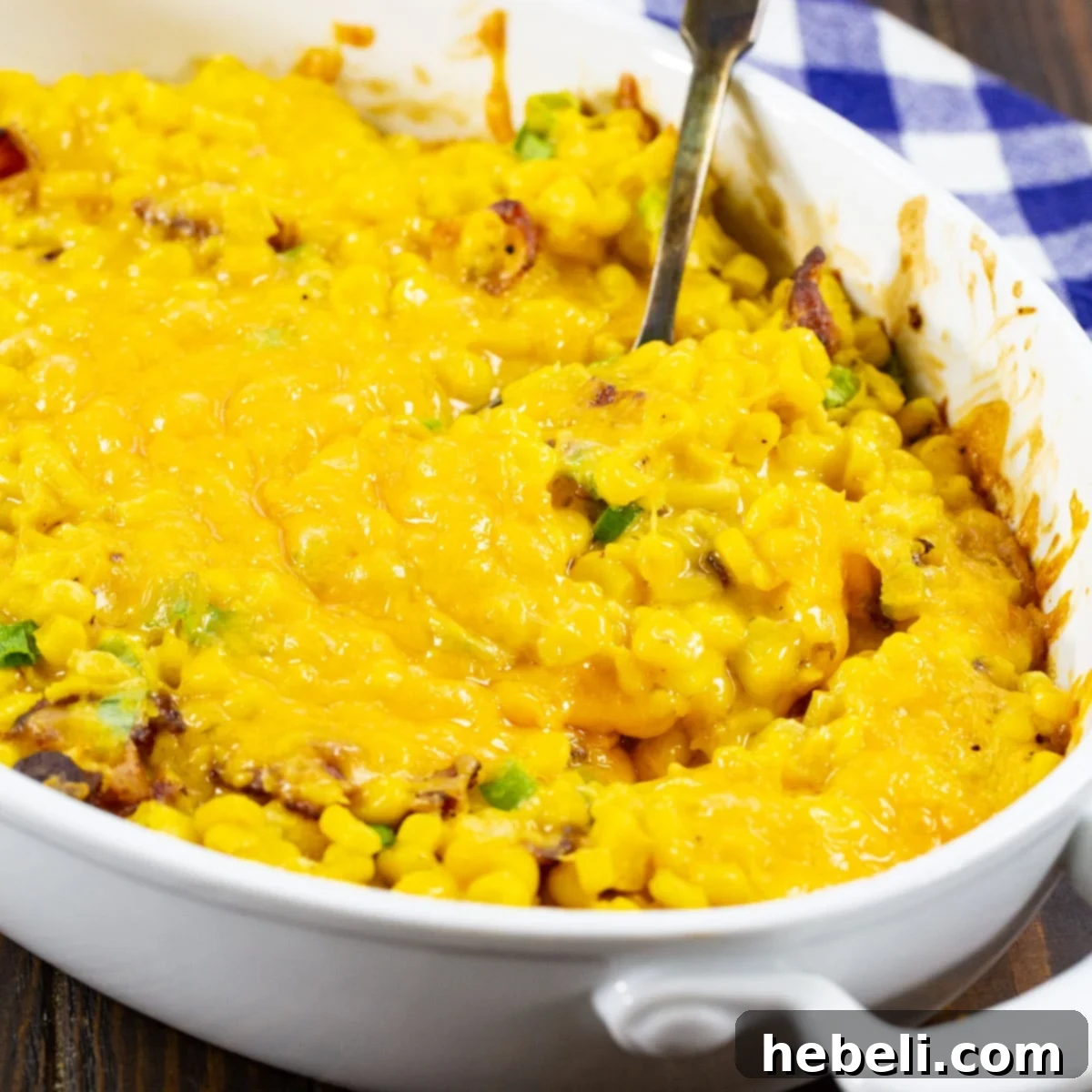 Cheesy Corn Casserole with Bacon in an oval baking dish, golden brown and bubbly from the oven.