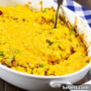 Cheesy Corn Casserole with Bacon in an oval baking dish, freshly baked and garnished with green onions.
