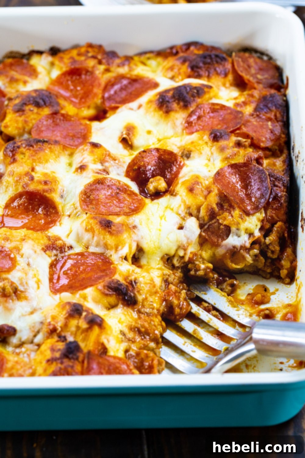 A close-up shot of Meat Lovers Bubble Up Pizza with a generous slice cut out, showing the layers of biscuit, sausage, pepperoni, and melted cheese.