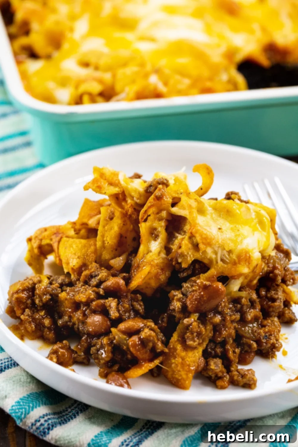 A generous serving of Sloppy Joe Frito Casserole on a white plate, showing melted cheese, crispy Fritos, and the savory meat mixture.