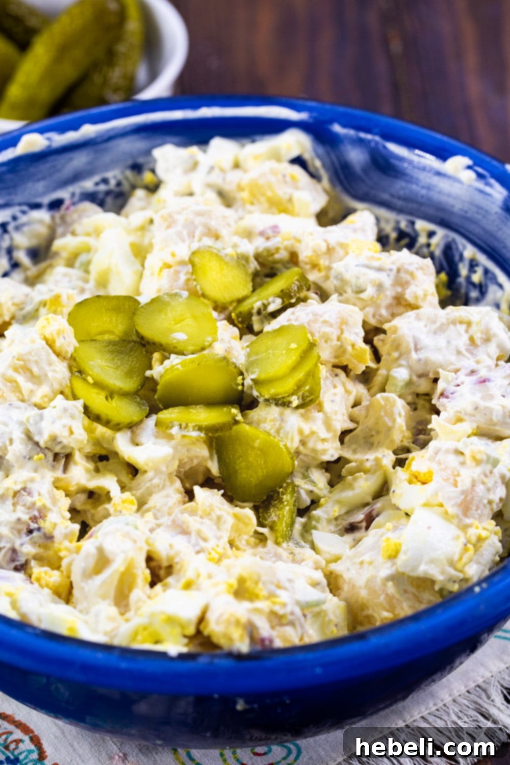 Potato salad topped with dill pickle slices.
