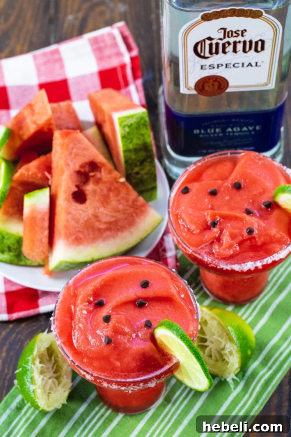 Icy Watermelon Margarita Bliss 3 Two Frozen Watermelon Margaritas, a plate of fresh watermelon chunks, and a bottle of silver tequila, ready for a party.