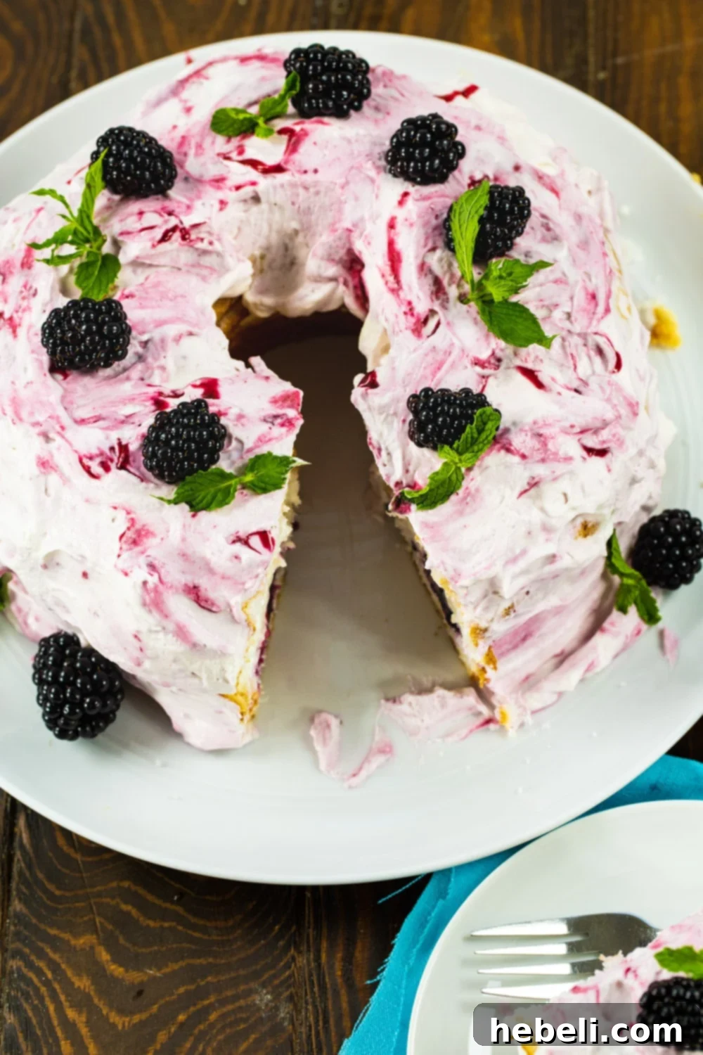 An angel food cake with a section cut out, revealing the blackberry and cream filling inside.