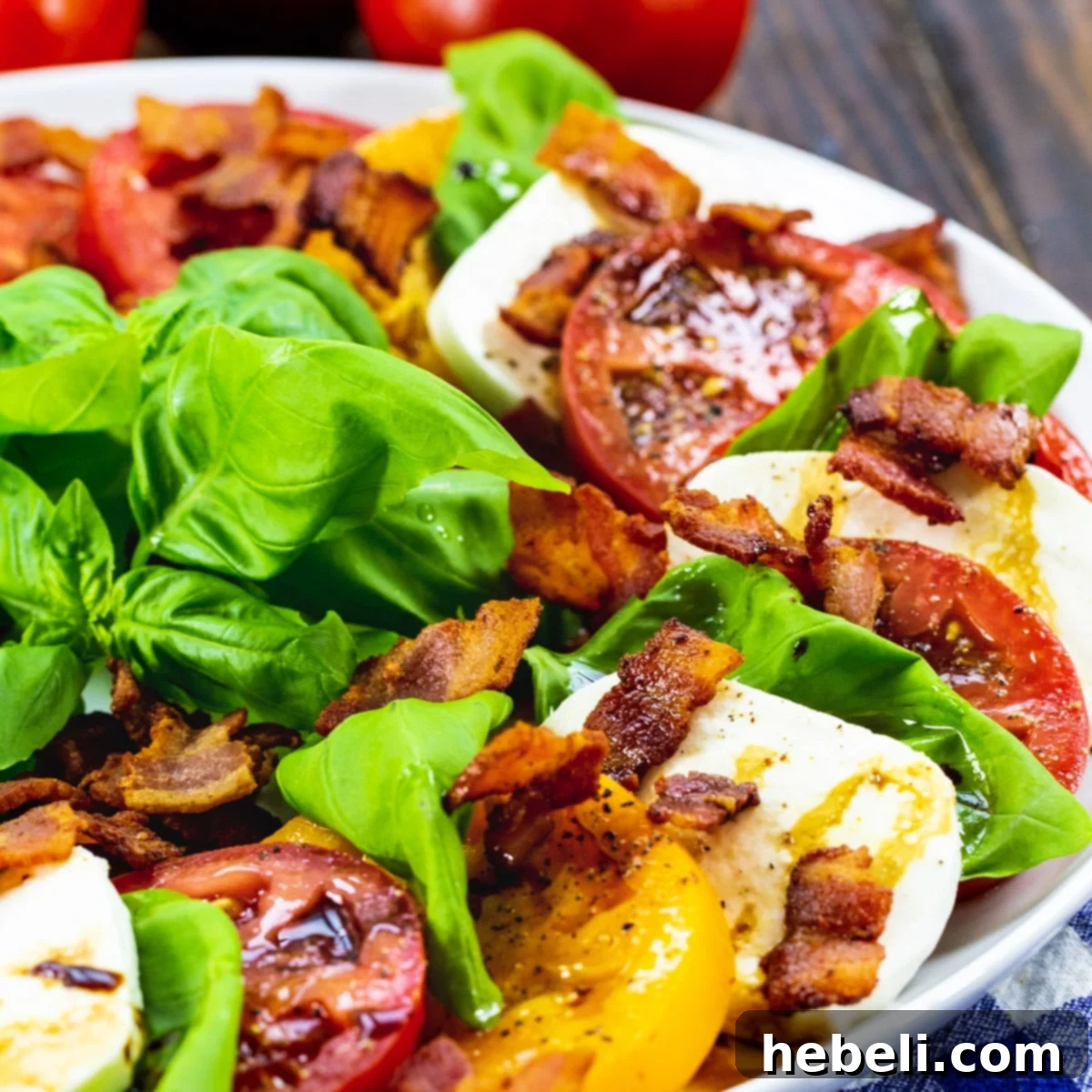 Bacon Caprese Salad artfully arranged on a large white plate, showcasing vibrant tomatoes, fresh mozzarella, green basil, and golden-brown bacon bits.