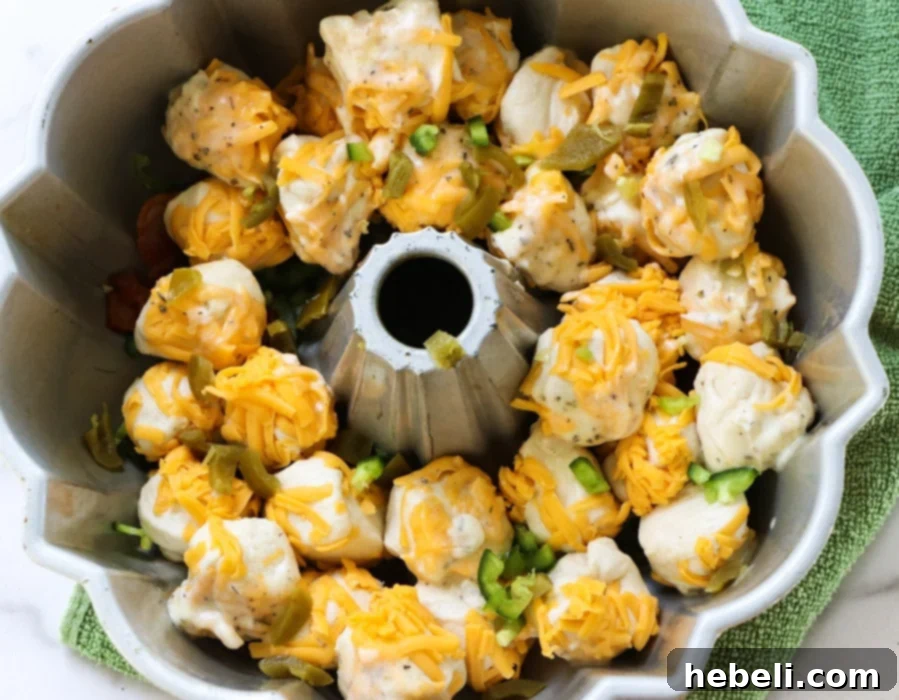 Gooey Jalapeno Cheese Bombs 4 Biscuit balls coated in cheese, arranged in the bundt pan.