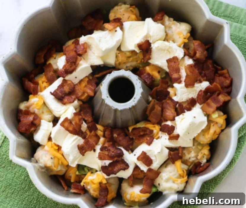 Gooey Jalapeno Cheese Bombs 5 Cream cheese pieces and bacon placed on top of biscuit pieces, forming a middle layer.