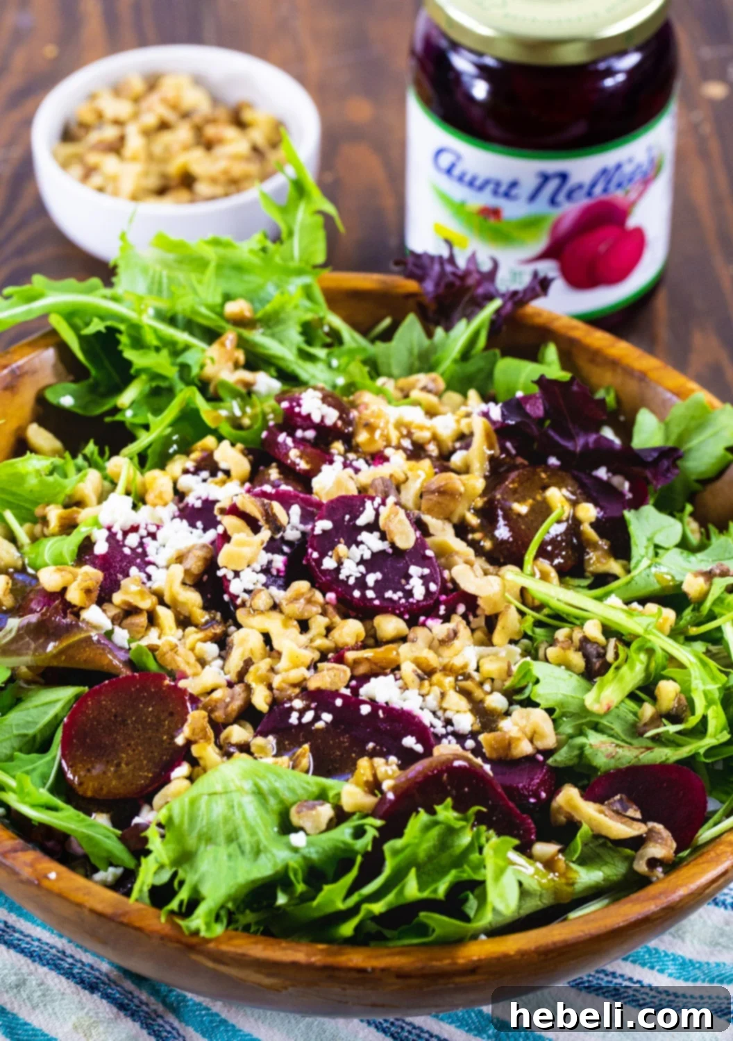 Pickled Beet Salad in a wooden bowl, alongside a jar of pickled beets and a bowl of walnuts, showcasing the fresh ingredients.