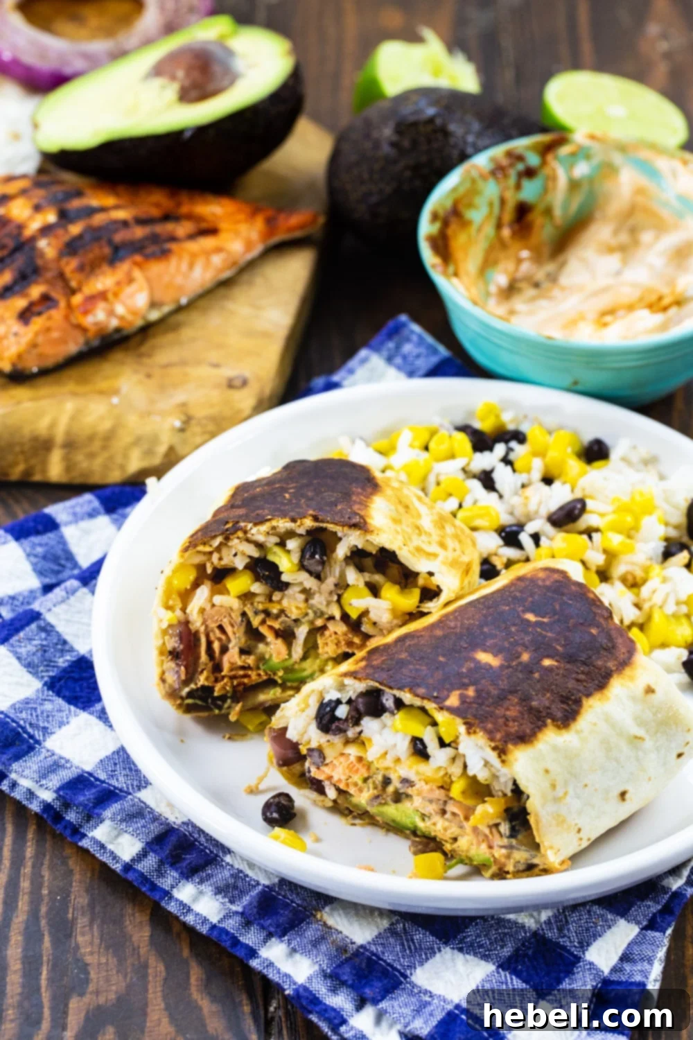 A Grilled Salmon Burrito cut in half, revealing the vibrant layers of salmon, rice, corn, and avocado inside.