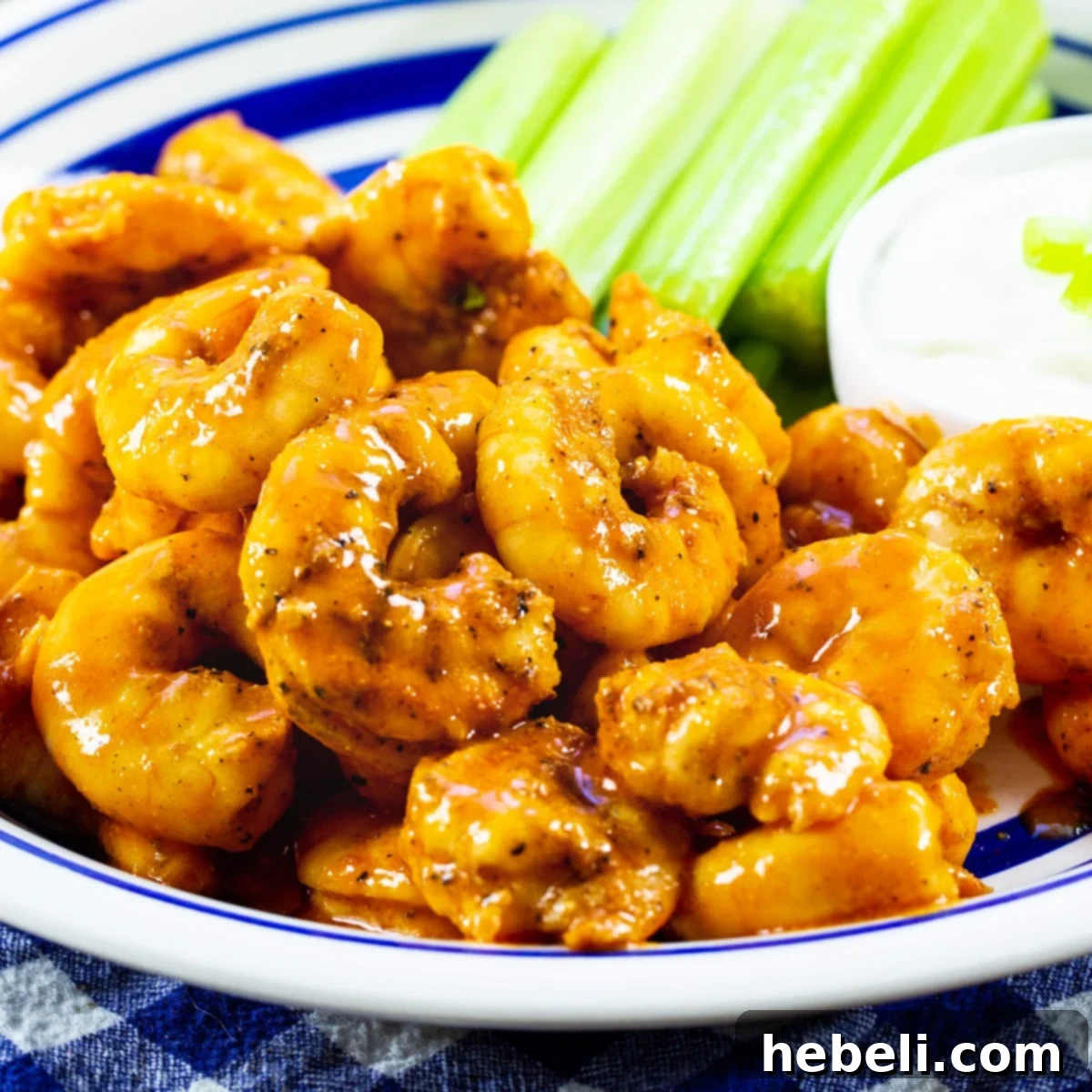 Spicy Buffalo Shrimp served on a plate with fresh celery sticks and a small bowl of creamy blue cheese dressing.