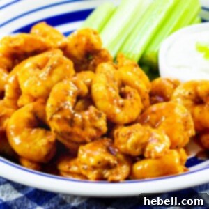 Buffalo Shrimp on a plate with celery and small bowl of dressing.