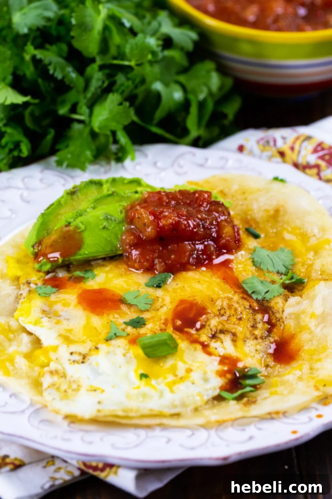 A rustic presentation of Tortilla Eggs on a plate, accompanied by a bunch of fresh cilantro, highlighting simple, fresh ingredients.