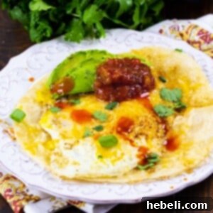 Tortilla Eggs topped with salsa and avocado on a plate.