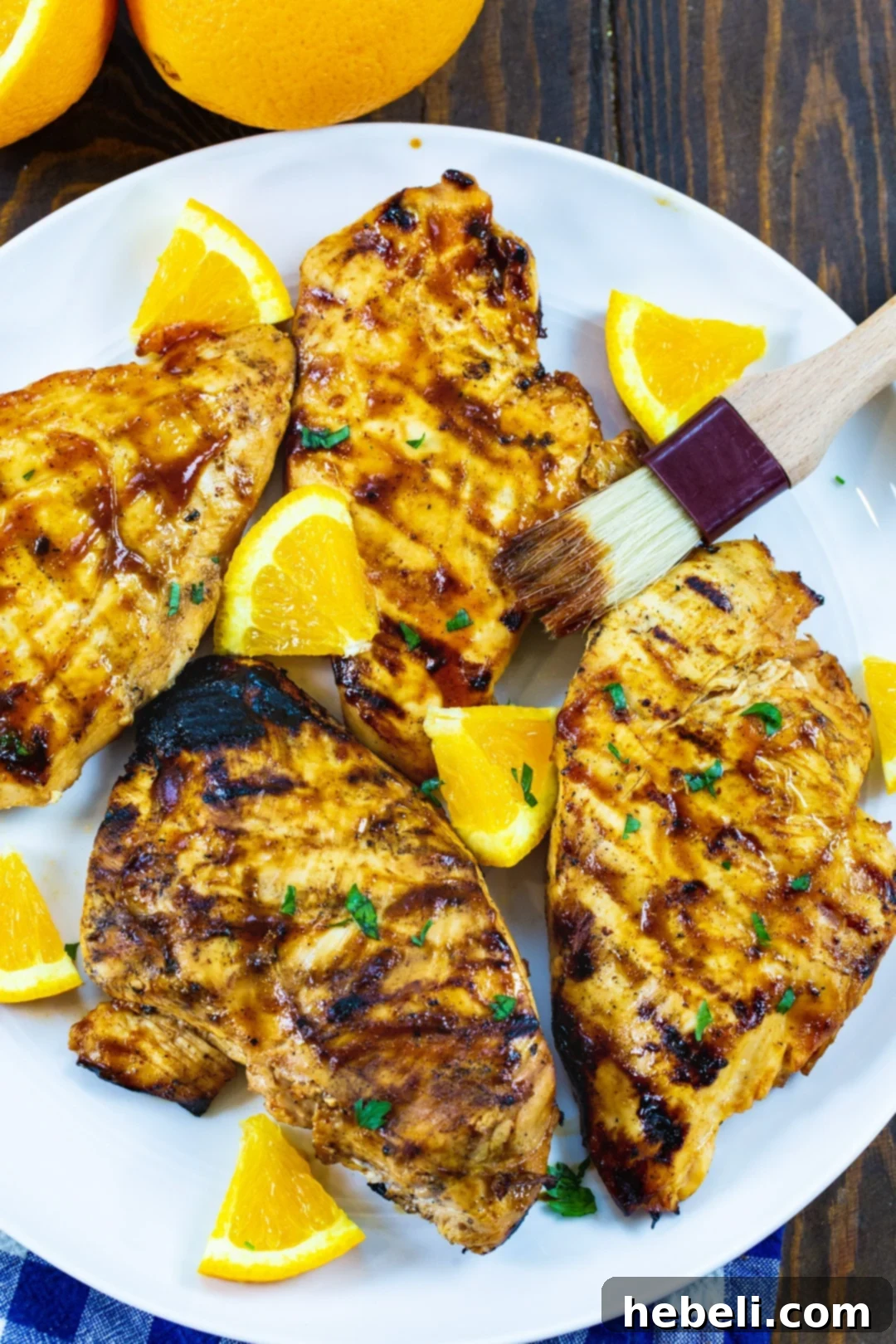 Flame Kissed Chipotle Orange Chicken 3 Perfectly grilled chicken breasts with prominent char marks, glistening with residual marinade, artfully arranged on a serving plate.